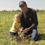 Ryan Boyd in alfalfa field with daughter